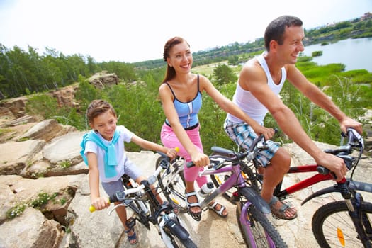 Portrait of family of three with bikes on a rock