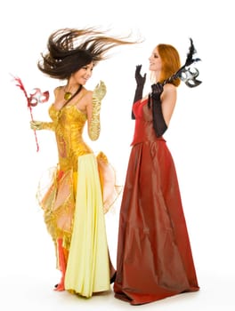 Photo of joyful actresses in fashionable dresses having fun over white background