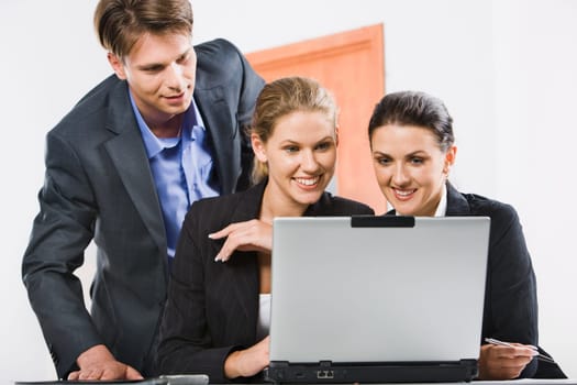 Businessman is looking at computer worked by two colleagues