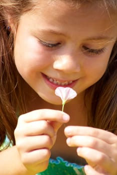 Close-up of girl enjoying nice smell of tiny flower