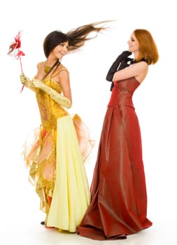 Photo of joyful actresses in fashionable dresses having fun over white background