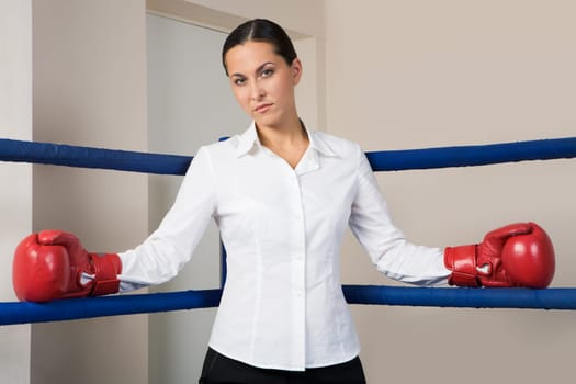 Portrait of strict businesswoman in boxing gloves looking at camera