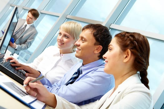 Portrait of working partners looking at laptop monitor in office and interacting
