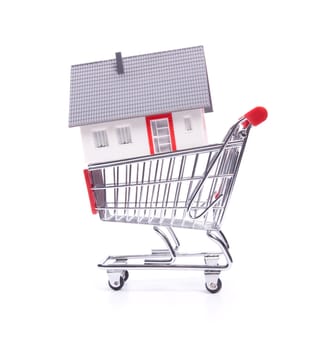 Buy new house concept - model of the house in shopping cart on white background.