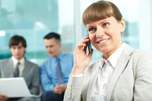 A beautiful businesswoman talking by cellular phone in working environment
