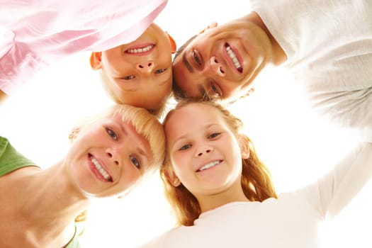 Below view of family members head by head smiling at camera