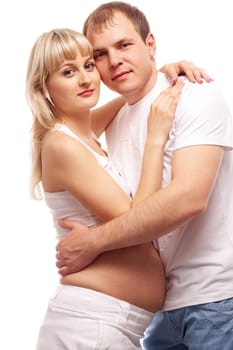 Image of pregnant woman and her husband embracing and looking at camera