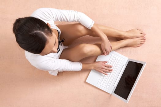 View from above of girl sitting and typing on laptop