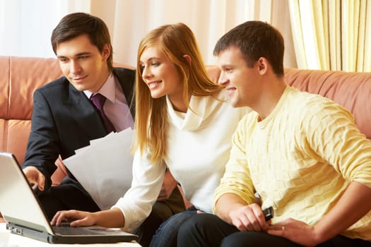 Portrait of a businessman and young couple looking at something in laptop