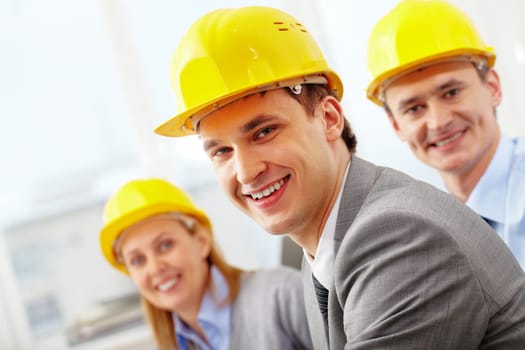 A smiling architect in helmet against his two colleagues