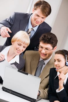 Portrait of four successful professional gathered together around the laptop
