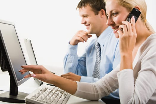 Portrait of business woman calling on the phone pointing to the monitor on a background of her colleague