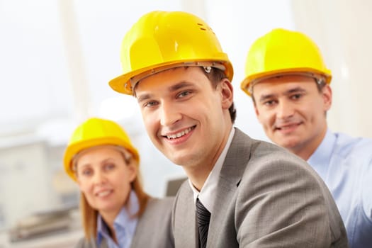 A smiling architect in helmet against his two colleagues