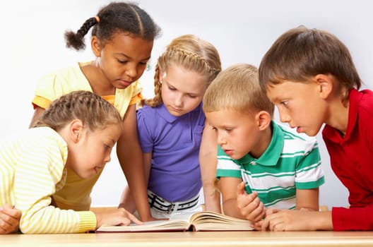 Portrait of pupils looking at page of encyclopaedia at reading lesson