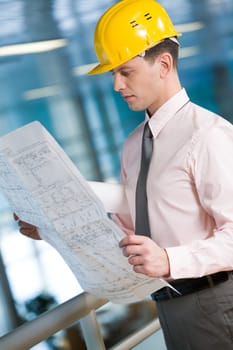 Portrait of confident foreman in helmet learning blueprint