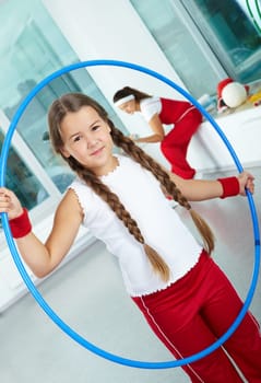 Portrait of healthy girl with blue hoop in gym
