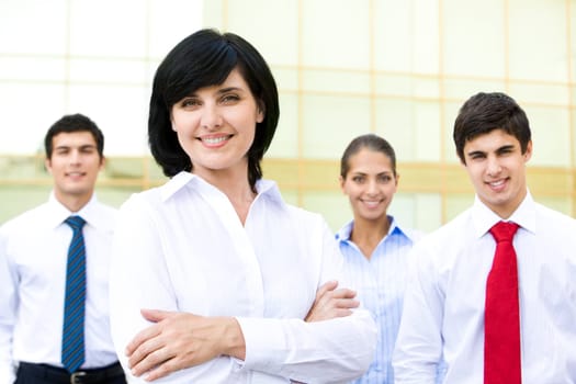 Portrait of pretty woman smiling at camera with business partners at background