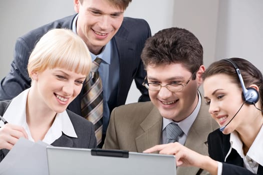 Team of four business people seriously gazing at a screen of laptop