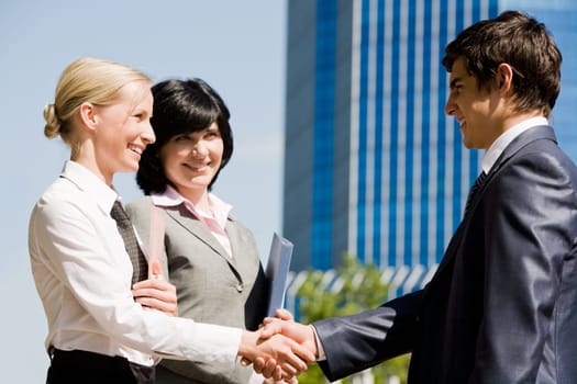 Photo of successful associates handshaking after striking deal outdoors at meeting