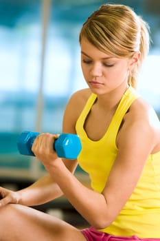 Portrait of young female with dumbbells doing exercises for strong arms