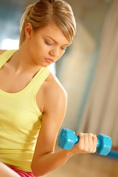 Portrait of young female with dumbbells doing exercises for strong arms