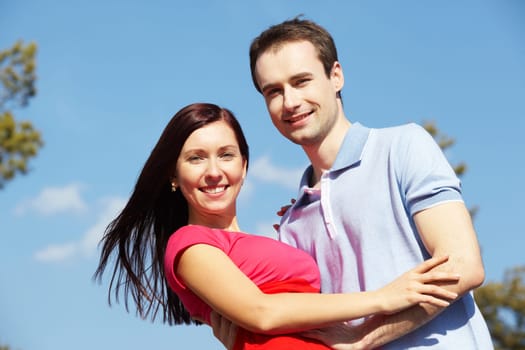 Portrait of happy couple looking at camera against blue sky