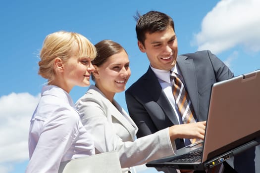 Photo of successful business partners looking at laptop during work