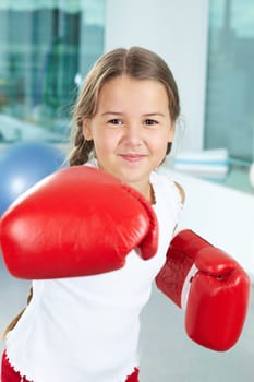 Portrait of pretty girl in boxing gloves in the gym