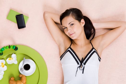 View from above of fresh girl lying on bed and looking at camera with smile