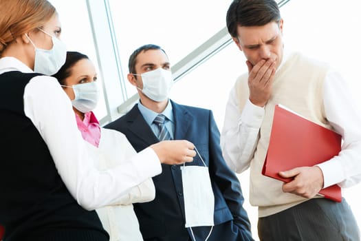 Group of associates in protective masks giving one to sick man