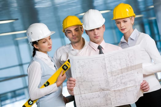 Portrait of confident architects in helmets learning blueprint