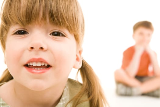 Face of small girl looking at camera on the background of her little brother