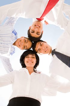 Below view of several successful partners embracing and looking at camera with smiles