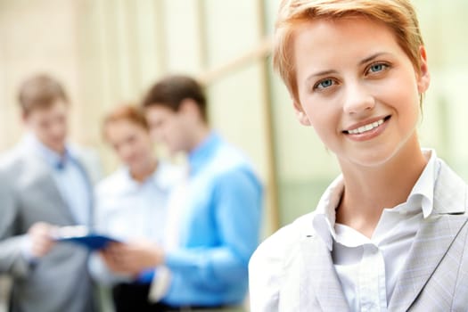 Portrait of pretty employee smiling at camera in working environment