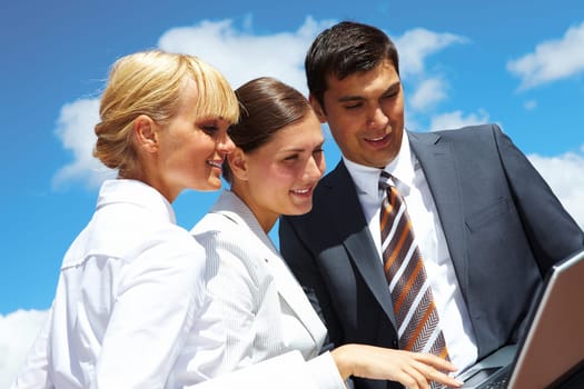 Photo of successful business partners looking at laptop during work