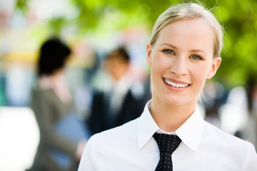 Portrait of pretty employee smiling at camera in a natural environment