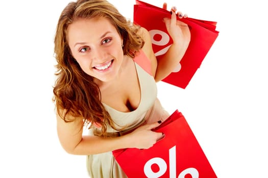 Above view of a girl holding paper bags with discount symbol, looking at camera and smiling