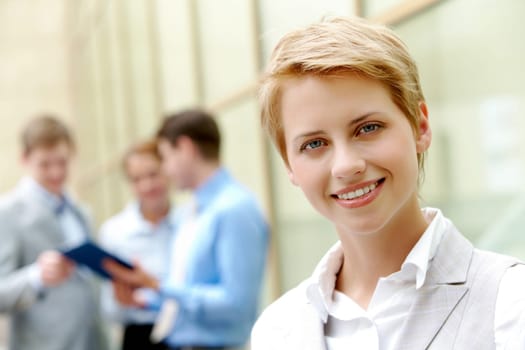 Portrait of pretty employee smiling at camera in natural environment