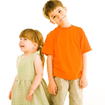 Portrait of small sister and brother standing next to each other over white background