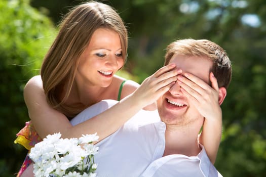 Photo of happy girl closing her boyfriend eyes by hands