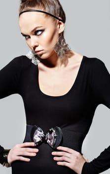Gorgeous woman with fantasy earrings posing on grey background