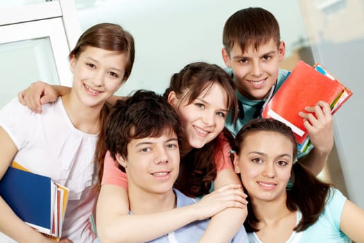 Portrait of five students embracing looking at camera and smiling