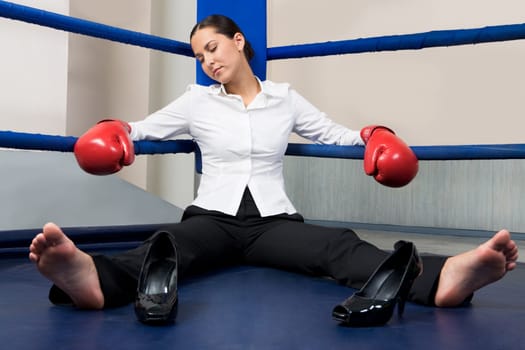 Portrait of tired businesswoman in boxing gloves sleeping on boxing ring