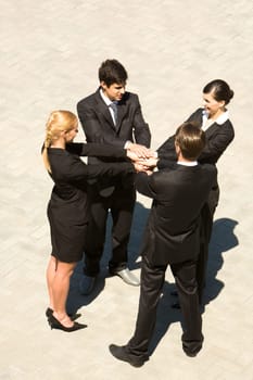 Photo of people standing and stacking their hands
