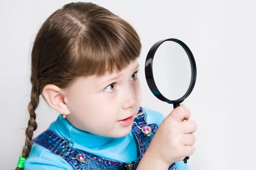 Close-up of small girl holding looking glass in hand and watching through it