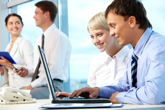 Portrait of executive partners looking at laptop display while working in office