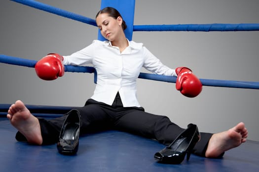 Portrait of tired businesswoman in boxing gloves sleeping on boxing ring
