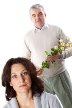 Portrait of mid aged brunette looking at camera with man holding flowers behind her