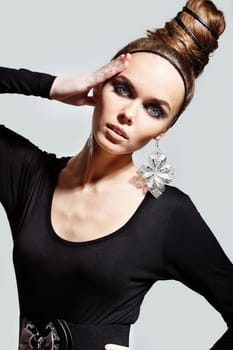 Gorgeous woman with fantasy earrings posing on grey background
