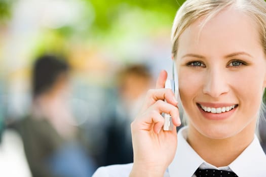 Portrait of pretty business woman talking by mobile phone and looking at camera with smile